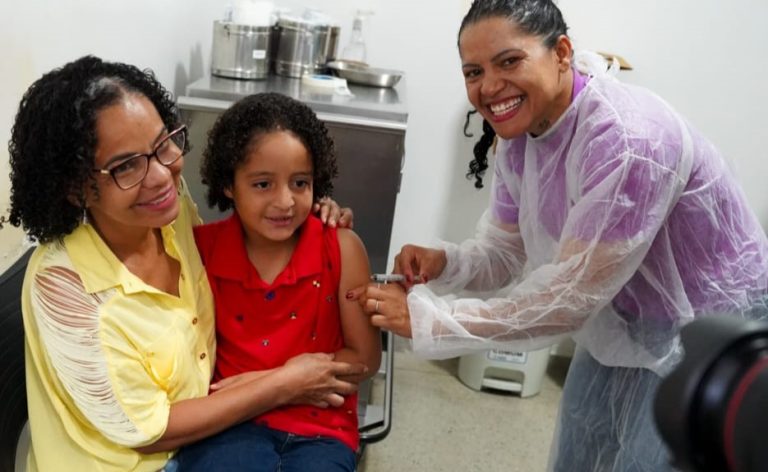 Goiânia e Aparecida antecipam ampliação da vacinação contra gripe - criança no colo da mãe recebendo vacina